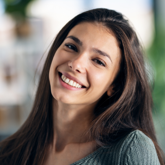 Patient holding up a dental shade guide guide to her teeth